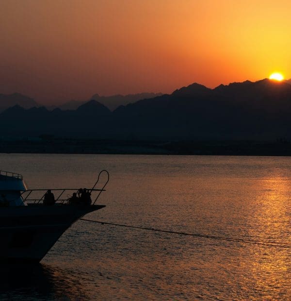 Sunset over mountains with silhouette of a boat.