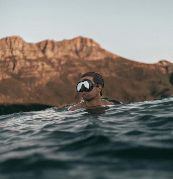 Man snorkeling in water with mountain background.