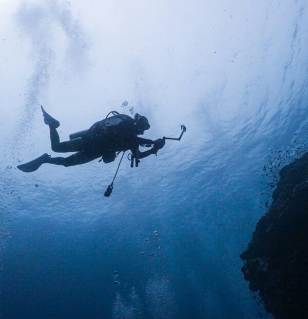 Scuba diver exploring underwater near rocky reef.