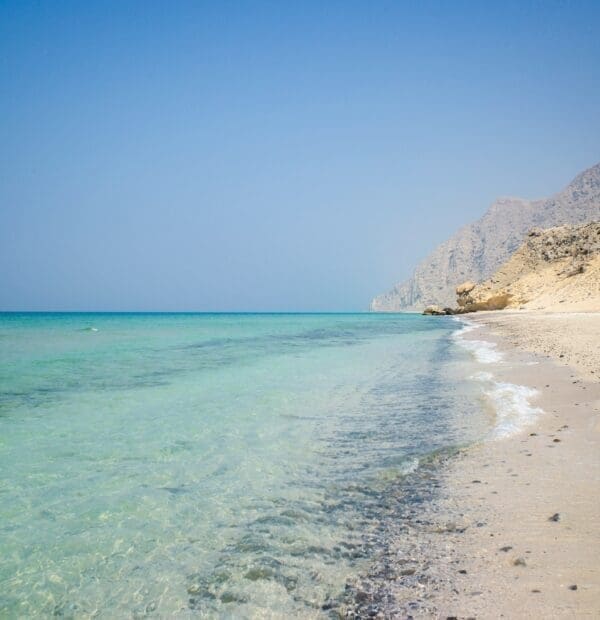 Serene beach with clear turquoise water and mountain backdrop