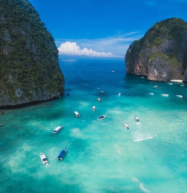 Tropical bay with boats and turquoise water surrounded by cliffs.