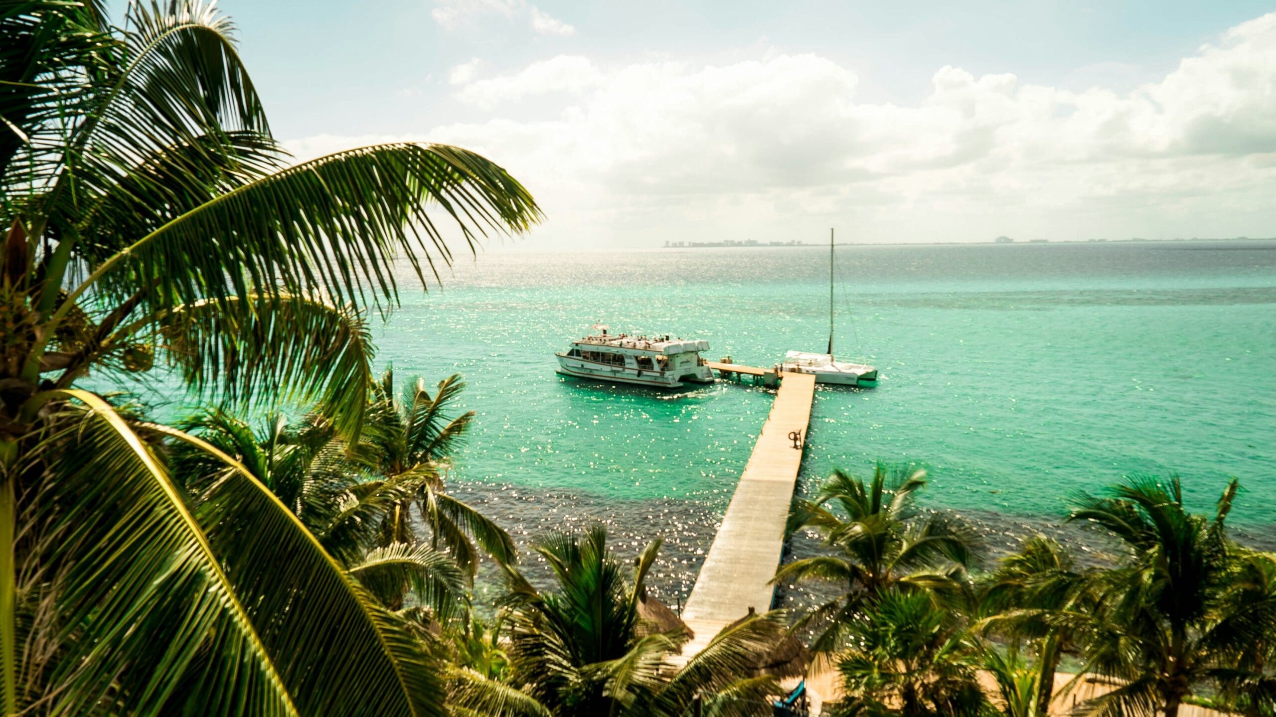 Tropical pier with boats and palm trees overlooking sea