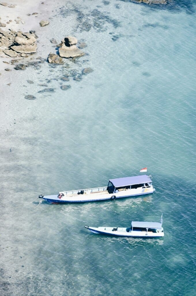 Two boats floating on clear turquoise water near shoreline