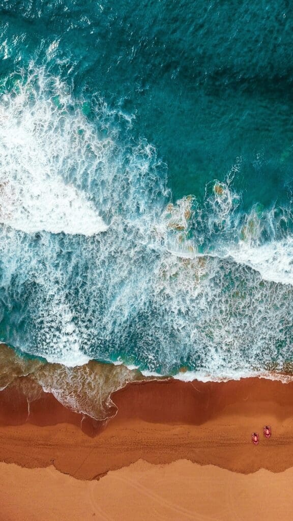 Aerial view of sandy beach with turquoise waves