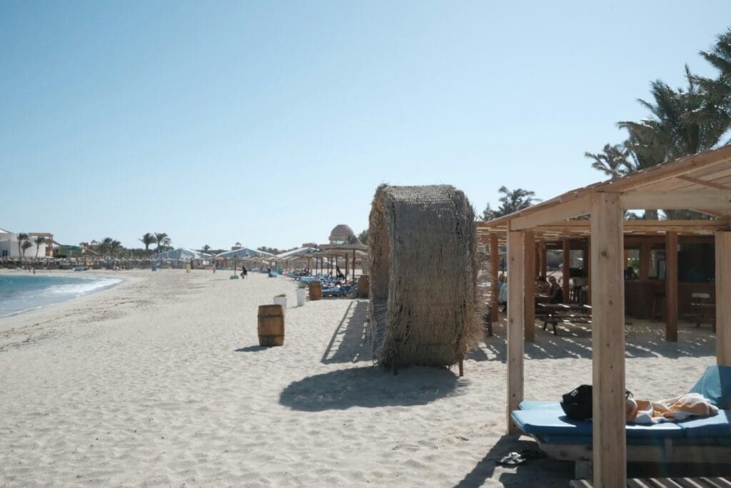 Sunny beach with umbrellas and visitors relaxing