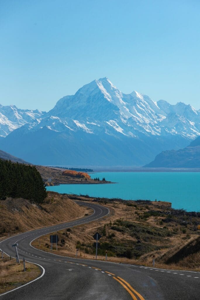 Winding road towards snowy mountain and turquoise lake