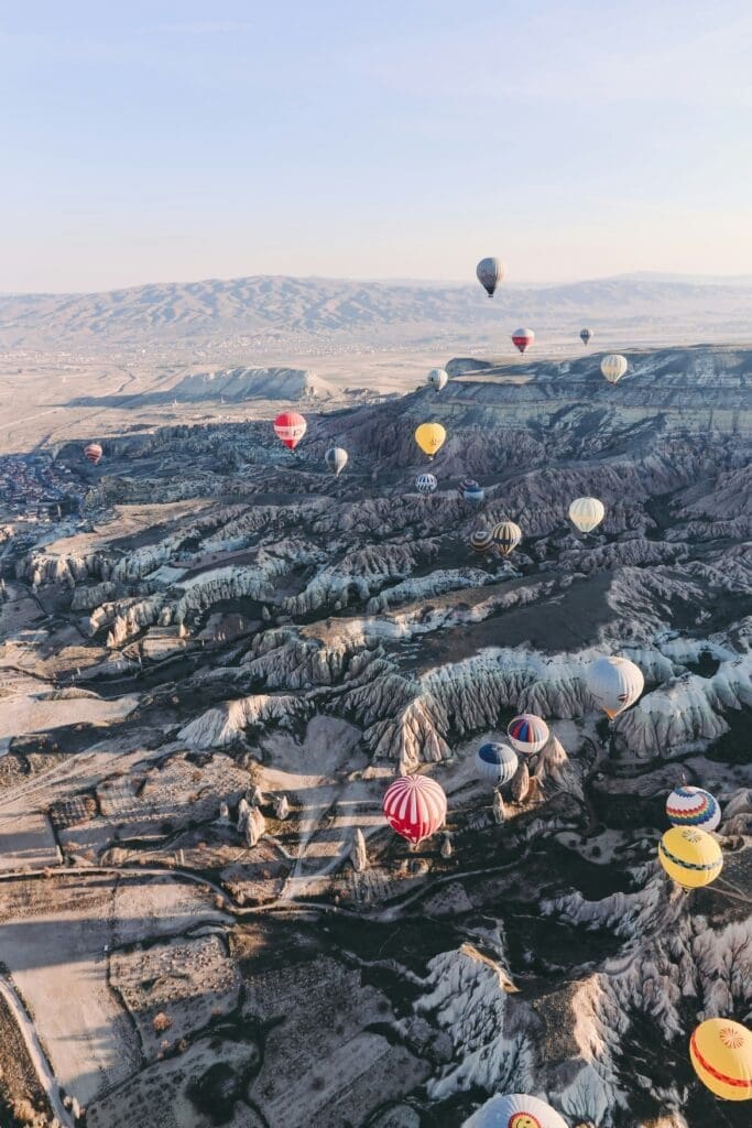 Colorful hot air balloons over rugged landscape at sunrise