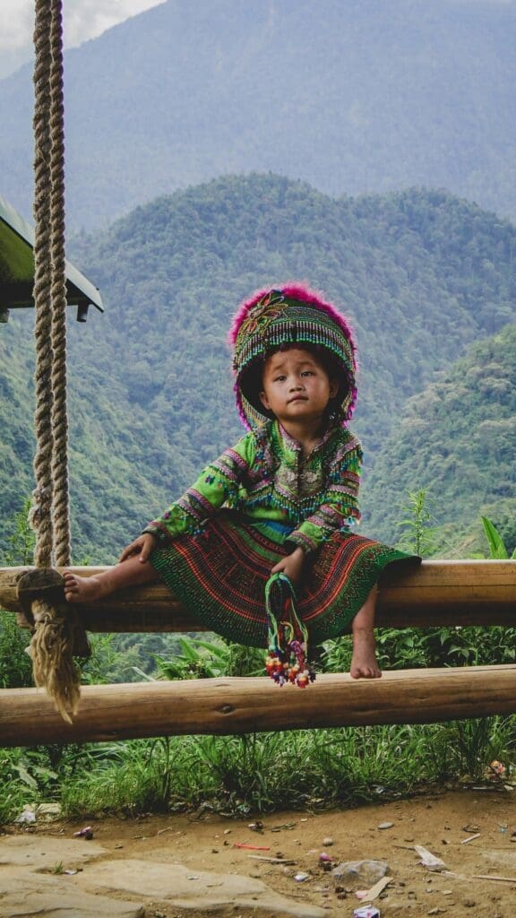 Young child in colorful tribal dress sitting outdoors